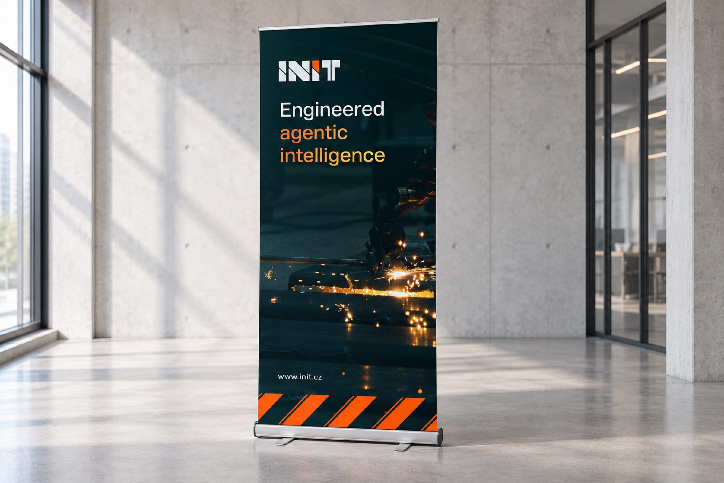A roll-up banner in a sunlit concrete lobby: Engineered agentic intelligence over sparks on a production line, orange hazard stripes at the base.