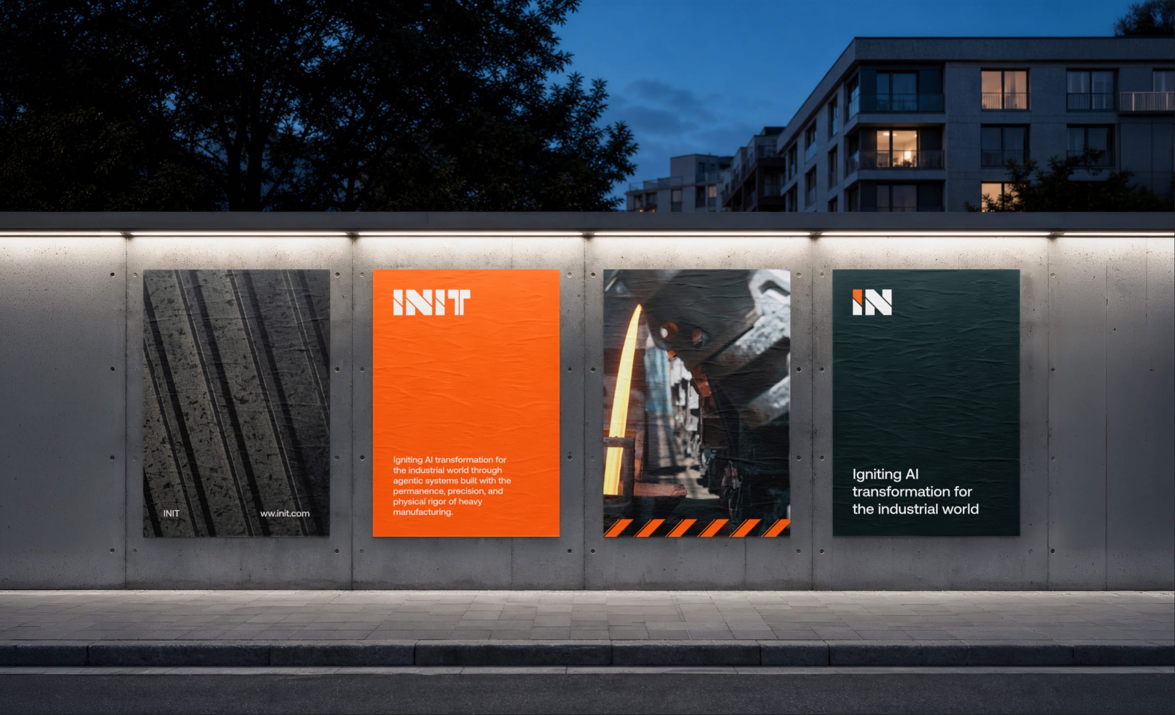 Four INIT posters on a lit concrete wall along a street at dusk: forged metal, the logotype on orange, molten steel, and the IN symbol on dark teal.