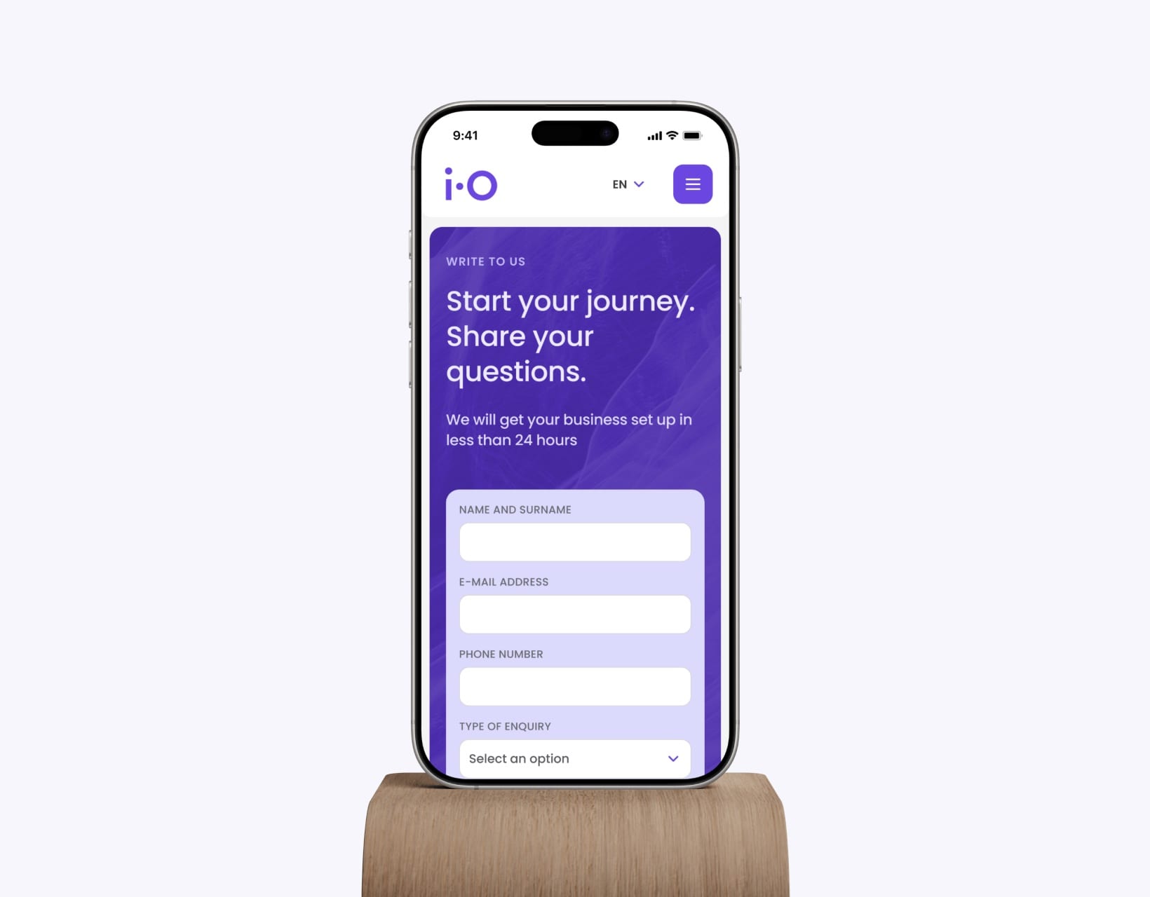 A phone on a wooden stand showing the iO Partners contact form: “Start your journey. Share your questions.”
