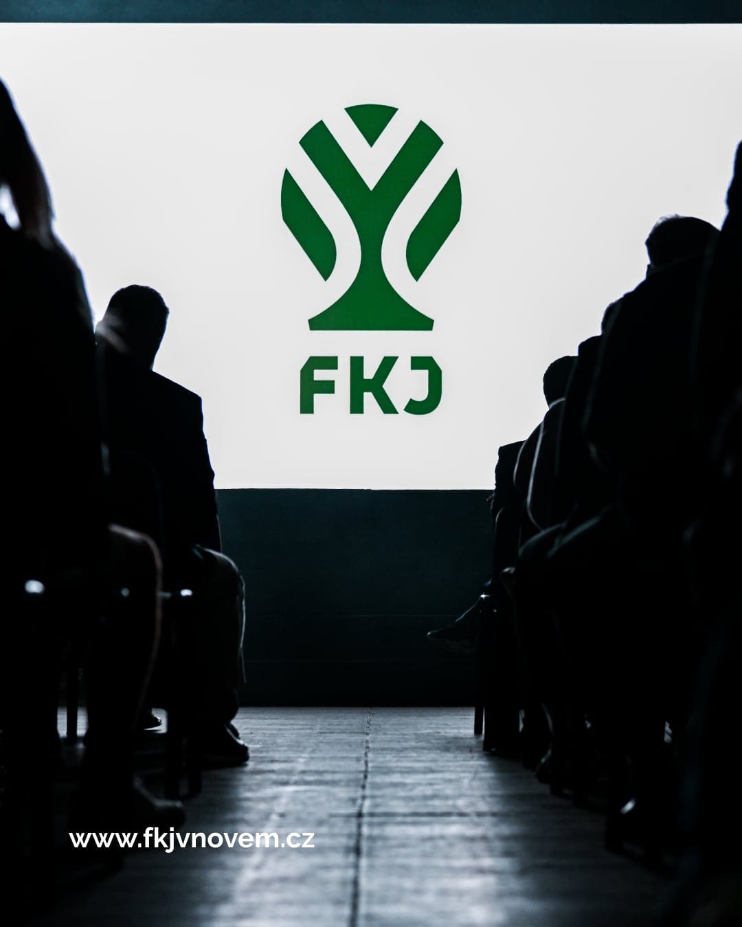 The FKJ apple-tree symbol projected on a big screen in front of a seated audience.