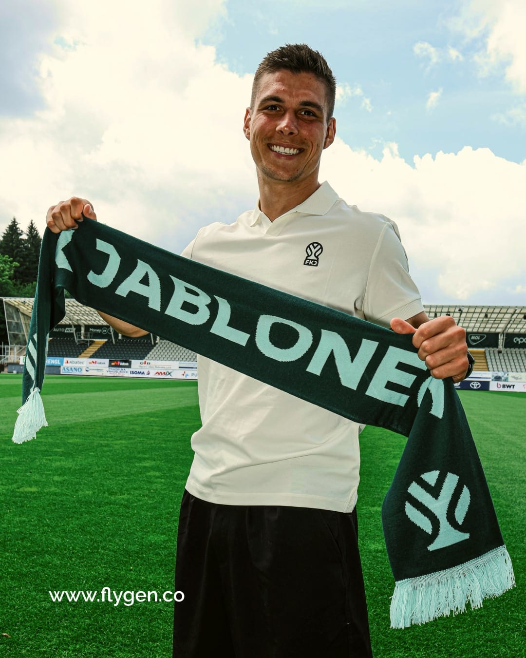 A player on the pitch holding up a green FK Jablonec scarf with the new symbol.