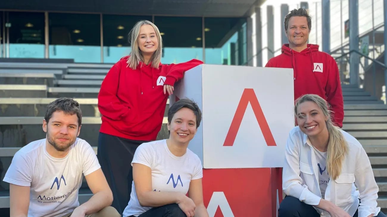 The Motionshift team at Antler, in red hoodies, around the Antler logo.