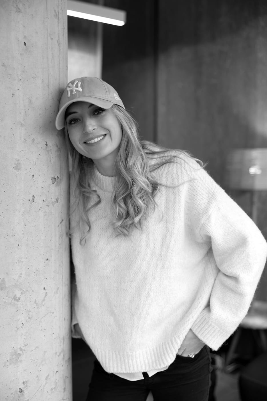Lucie Krulichová smiling, leaning against a concrete pillar.